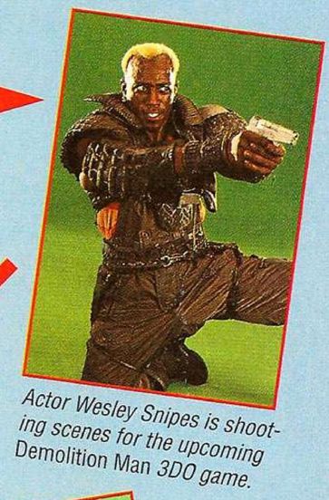 a close-up of wesley snipes, bright short dyed blonde hair, kneeling and pointing his gun against a green screen. he is wearing black futuristic clothes.
caption: actor wesley snipes is shooting scenes for the upcoming demotlition man 3do game.