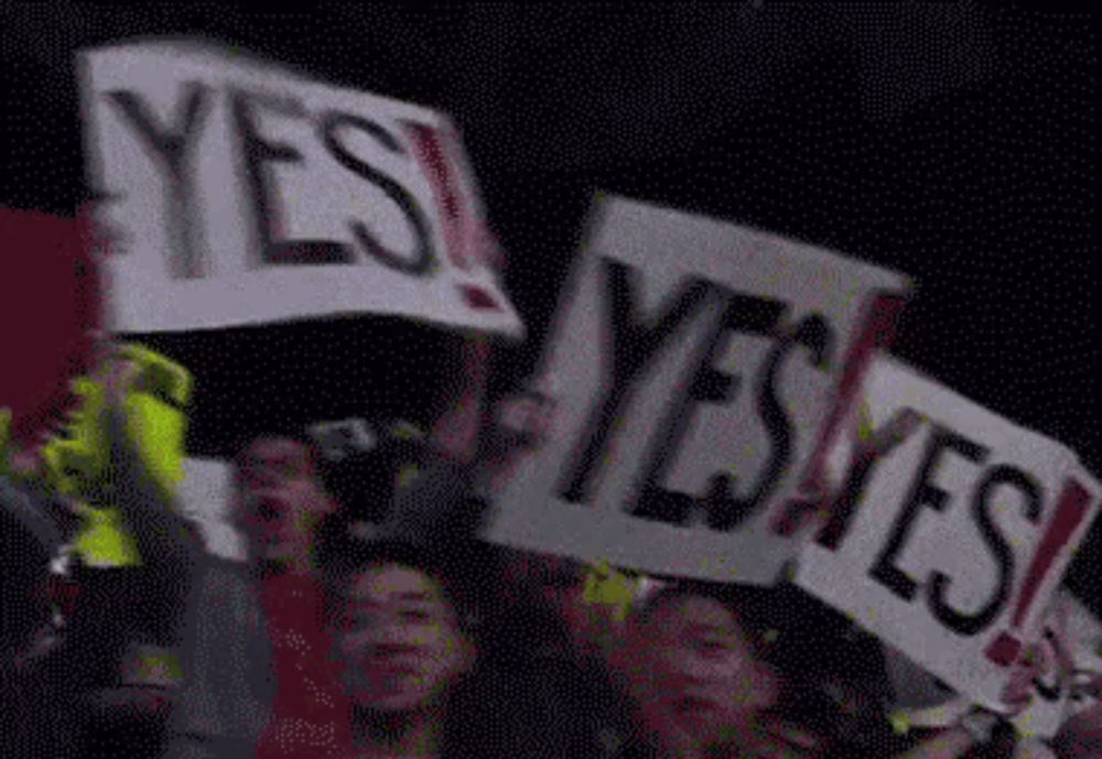 a crowd of people holding signs that say yes