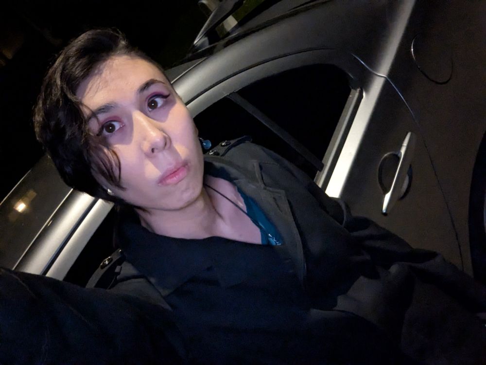 A selfie of Alice leaning on her car at midnight 