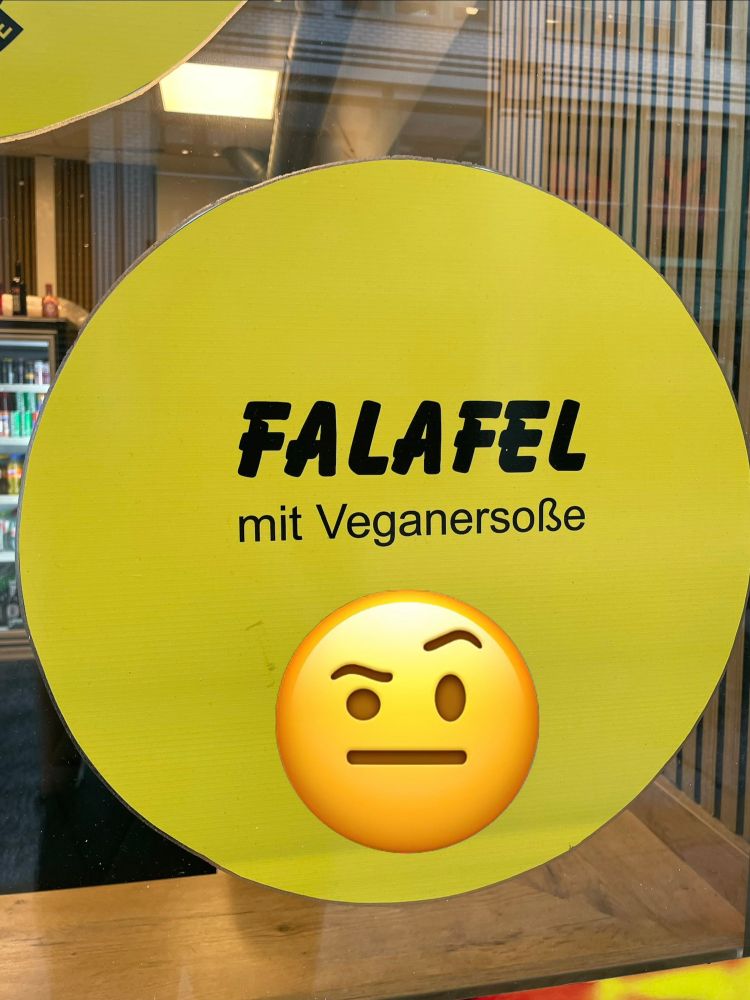 Aufkleber mit Werbung für Falafel. Anstatt „veganer Soße“ steht dort „Veganersoße“ in einem Wort.