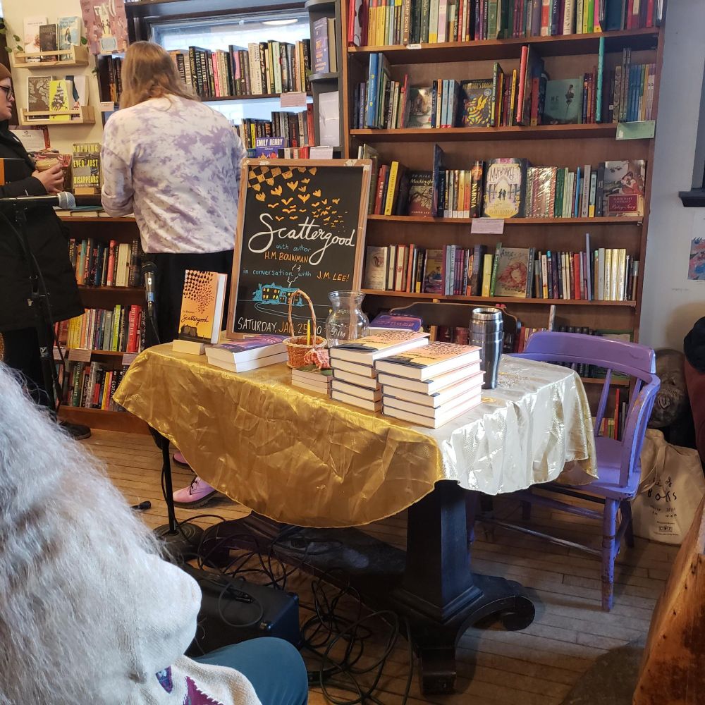 photograph of a signing table at Wild Rumpus Book store, stacked with SCATTERGOODS (h.m. bouwman) and even a couple THE NIGHTLAND EXPRESS (j.m. lee)
