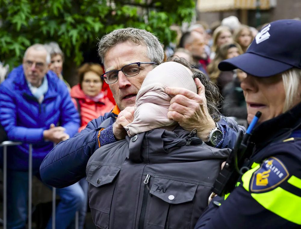 Pro-Palestinademonstrant wordt door de politie afgevoerd met over het gezicht getrokken pet om te voorkomen dat er iets verschrikkelijks gezegd wordt zoals Free Palestine.