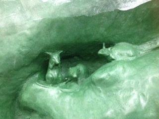An image of a large section of green wax with three rats crowding in a crevice. This is a section of the Peter Pan Statue being remade.