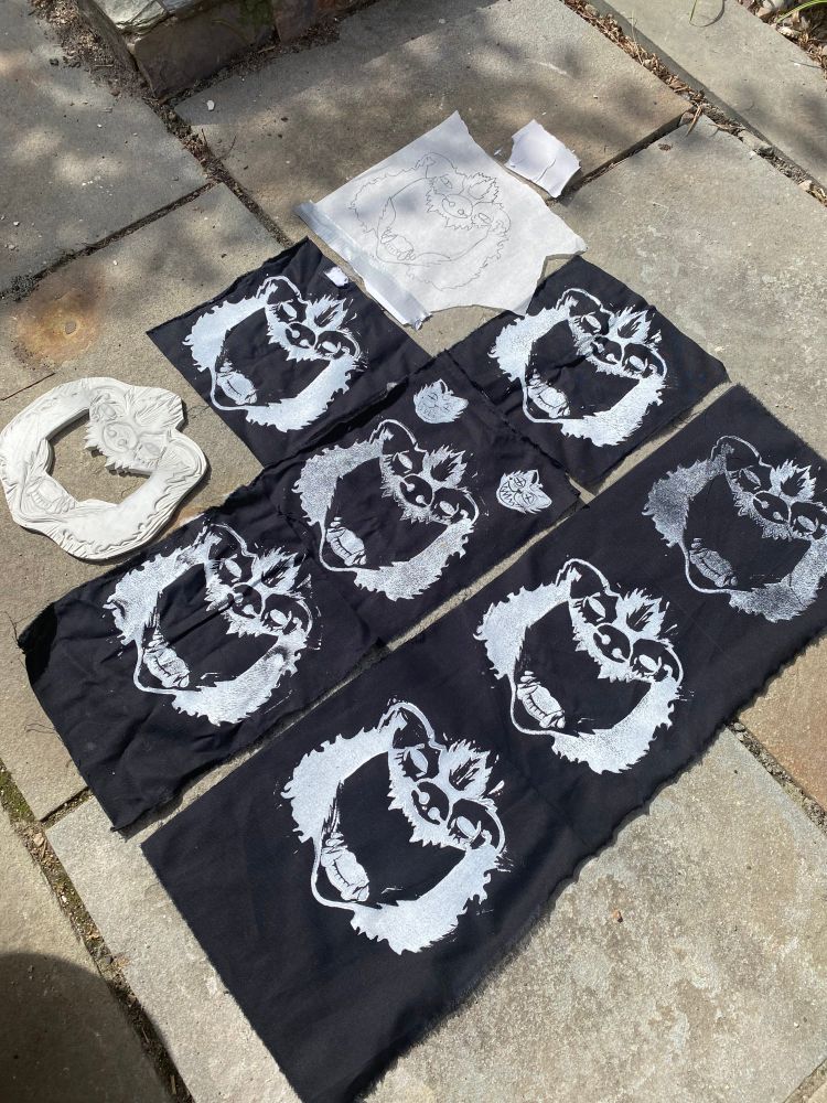 A zoomed out shot showing more of the patches alongside the carved stamp and the parchment paper sketch. 