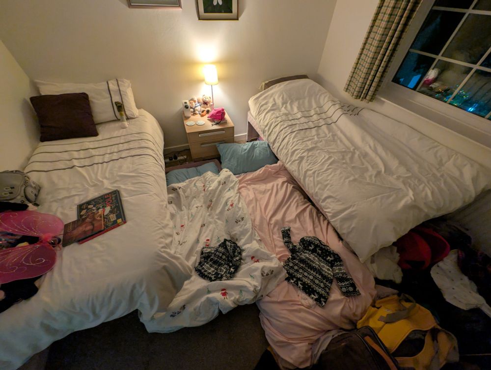 A cramped bedroom with four beds: two single and two kids' beds on the floor