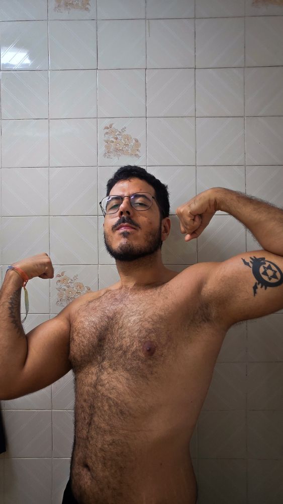 Foto minha sem camisa, da cintura pra cima, flexionando ambos os braços 
