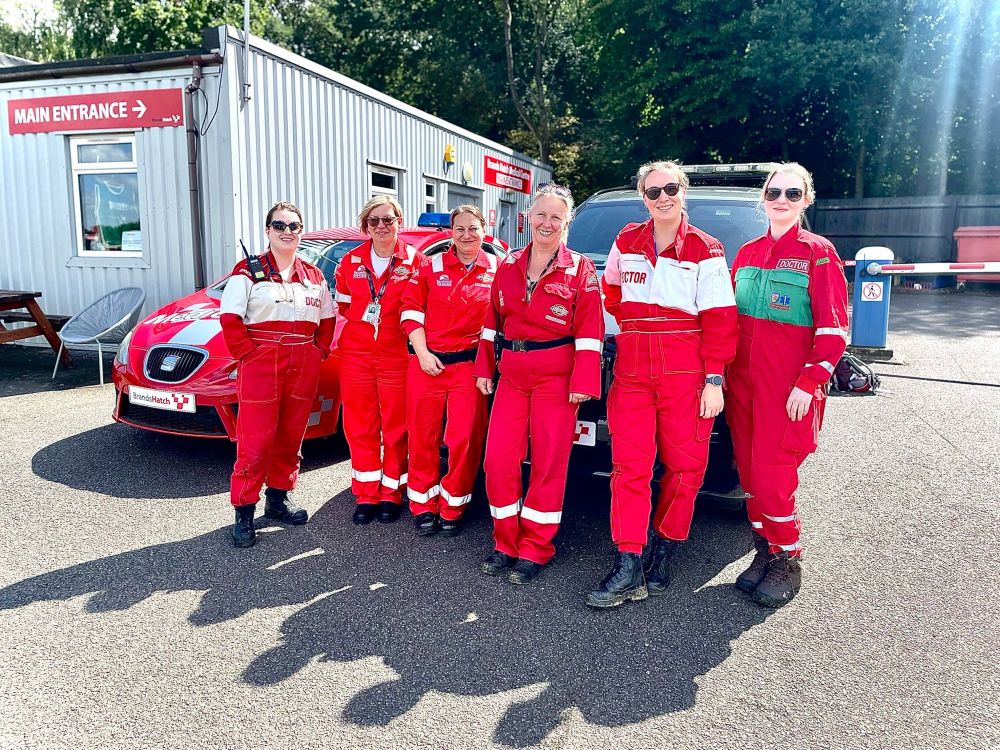 6 women in red motorsport overalls at work
