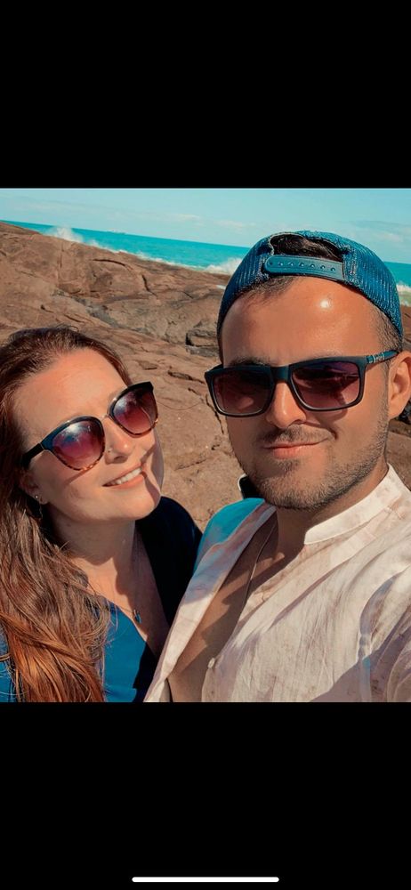 Me and my husband smiling and wearing sunglasses at the beach