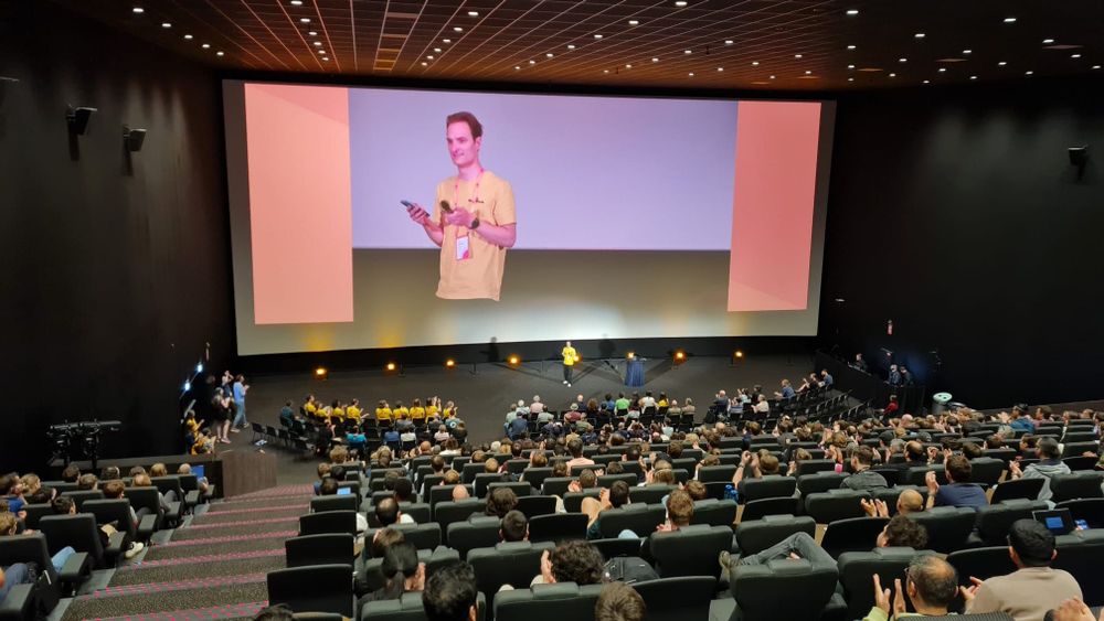 Picture shows Terts on the screen wrapping up the Conference in the Main Track room with the audience in the front.
