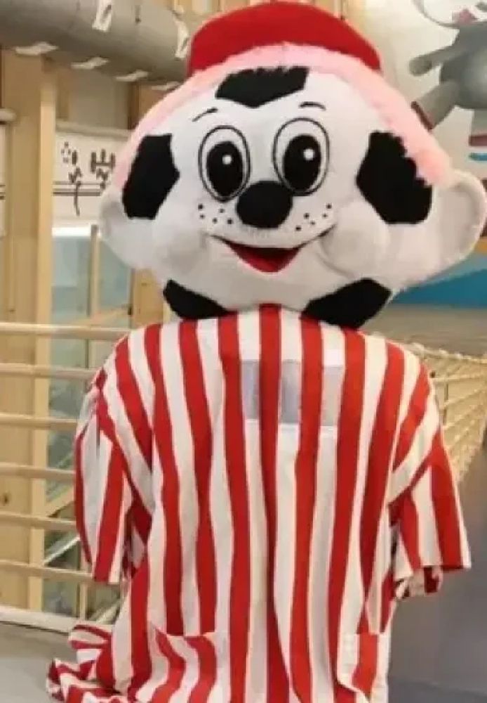 un disfraz de. mascota horrible, camiseta a rayas de fútbol y por cabeza un balón de fútbol. con ojos y sonrisita, como de felpa. 