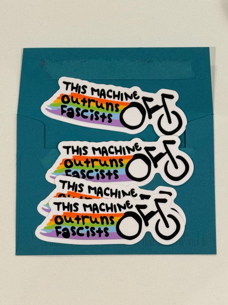 Two stickers, one large, one small, with a hand-drawn bicycle with a rainbow trail and the text "This Machine Outruns Fascists"