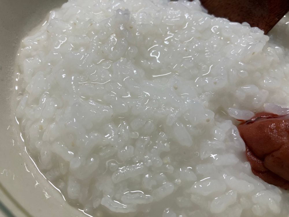 おかゆの写真。梅干しが載せてある。木の匙。