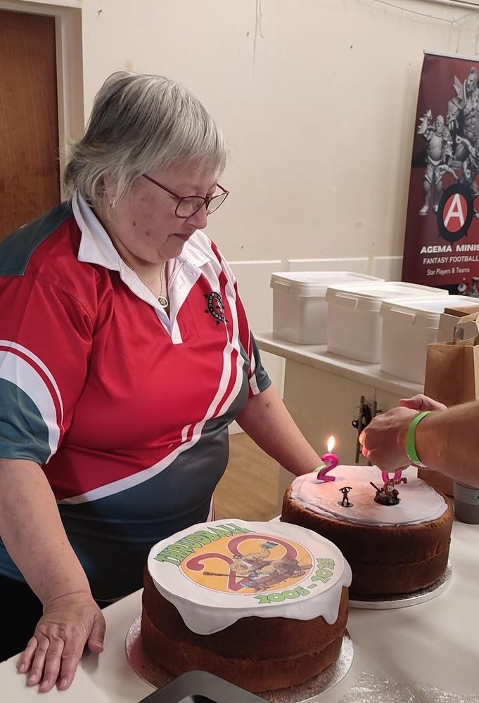 Luciferous Windmill at the cake stand looking over the two cakes she baked for the Event