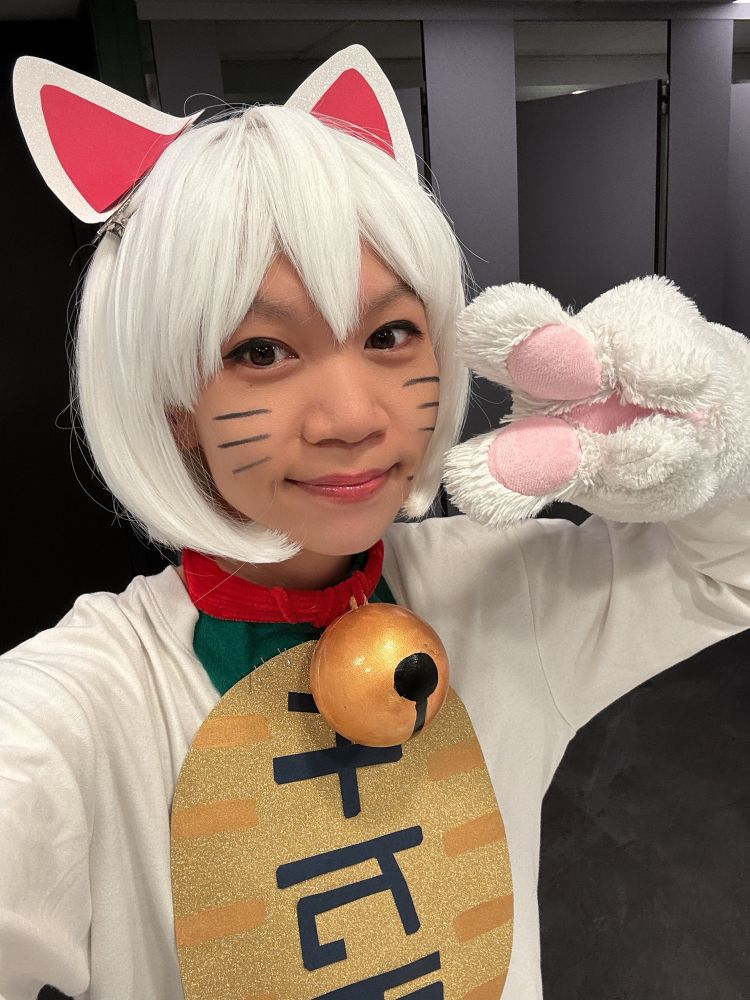 Photo of me dressed as turbo granny for Halloween smiling putting up a peace sign with a hand wearing a giant cat paw glove 