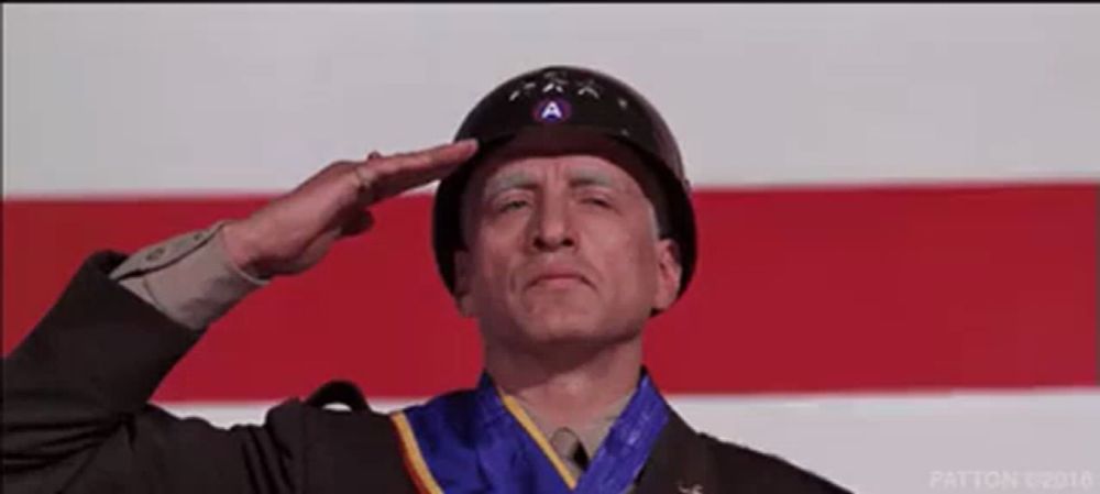 a man in a military uniform salutes in front of an american flag ..