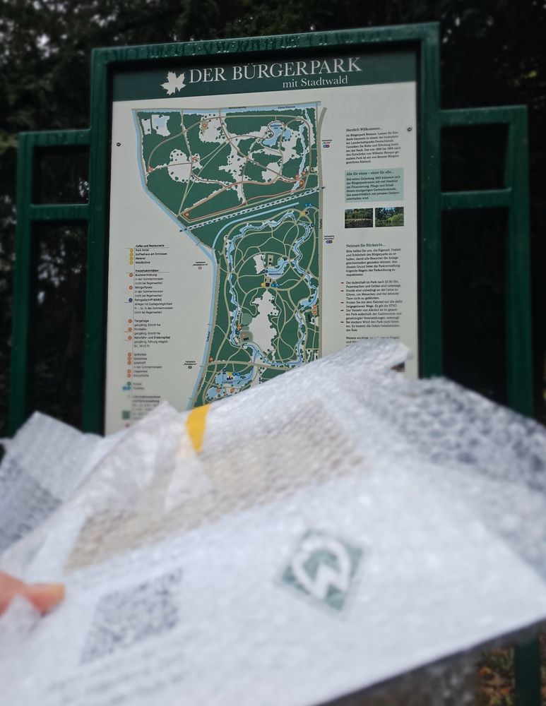 Bild der Wegetafel im Bremer Bürgerpark und davor die noch verpackte neue Infotafel zu einem Werder Ort