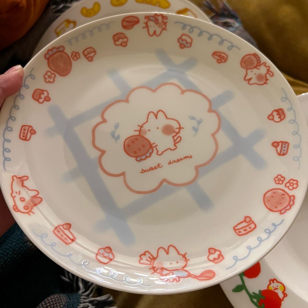 a dessert plate with drawings of kittens piping whipped cream amongst pastries