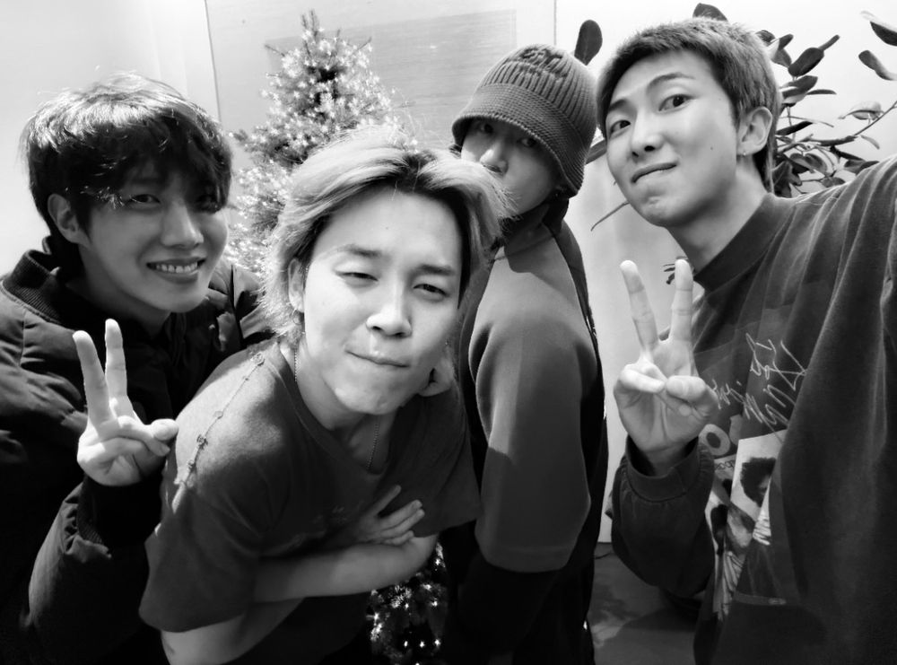 selfie de 4 integrantes do bts juntos: hoseok, jimin, jungkook e namjoon. hoseok e namjoon estão fazendo um V para a câmera enquanto o jimin está com os braços cruzados e fazendo uma careta meio sério e o jungkook está de lado atrás dele. 