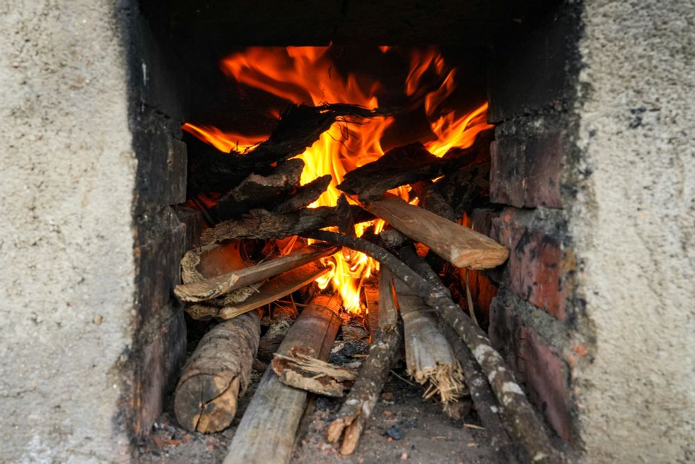 wood fire under a cast iron wok for the kill green phase of raw Puer tea production 