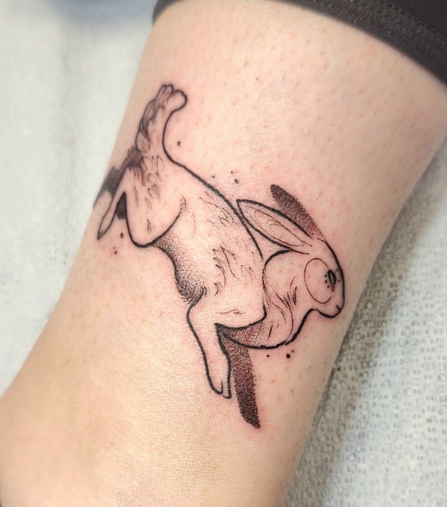 Blackwork tattoo of a hopping bunny