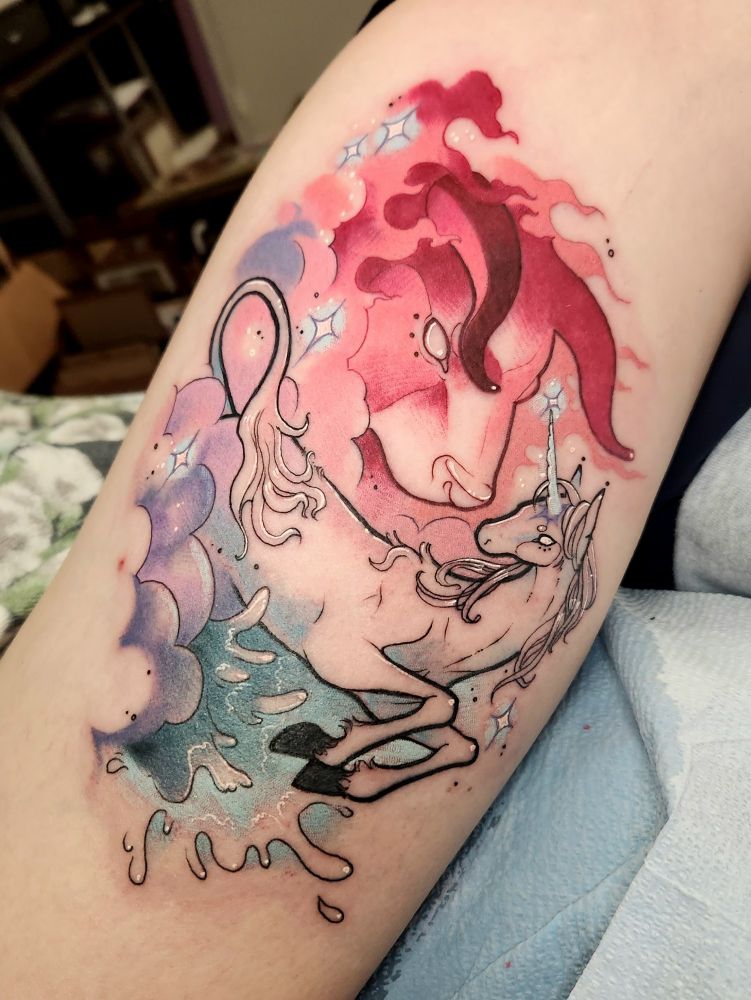 Tattoo of Amalthea the unicorn jumping in water, with a cloudy fiery bull in the background. 