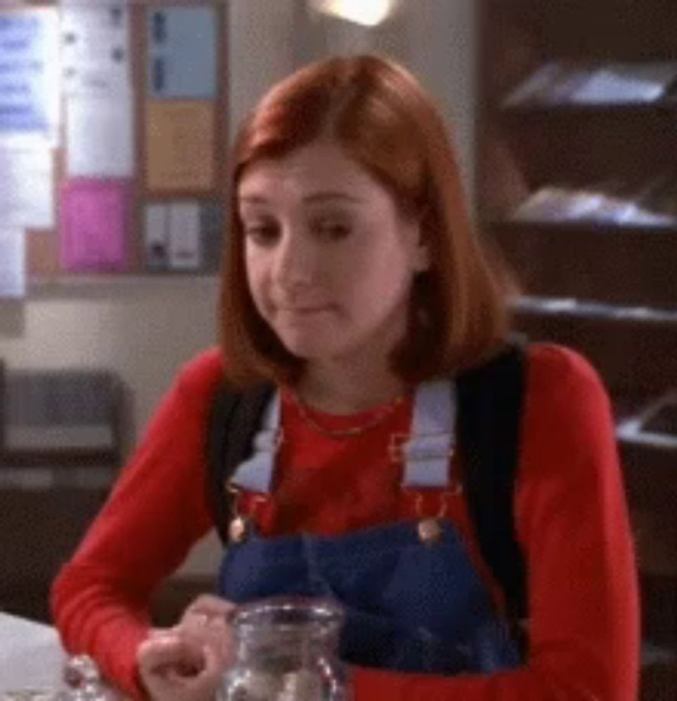 a woman in overalls is sitting at a table with a pitcher