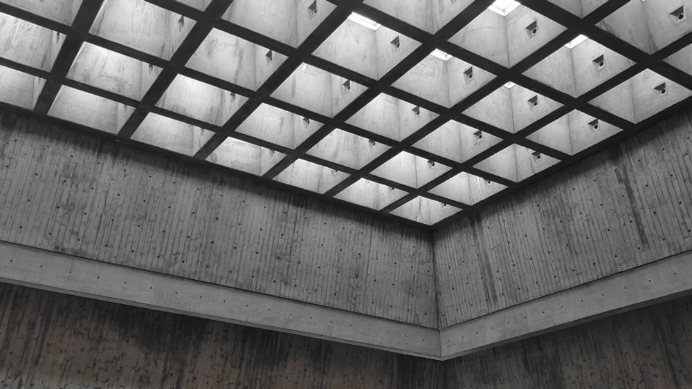 concrete brutalist walls and ceiling with light shining down from a square grid of skylights