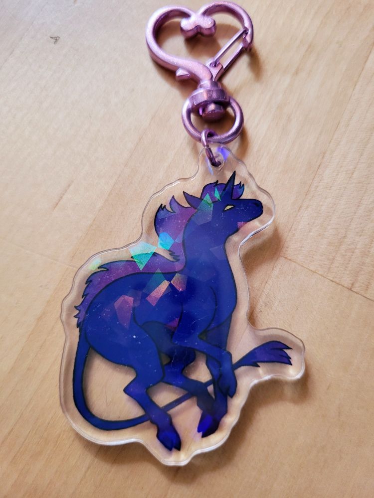 An acrylic charm of a dark purple unicorn