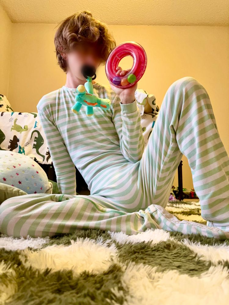 Rex is wearing his favorite green and white striped footies, underneath he is wearing a Tykables Camelot that is very bulgy. Playing with his favorite ring rattle and sucking on a pacifier!