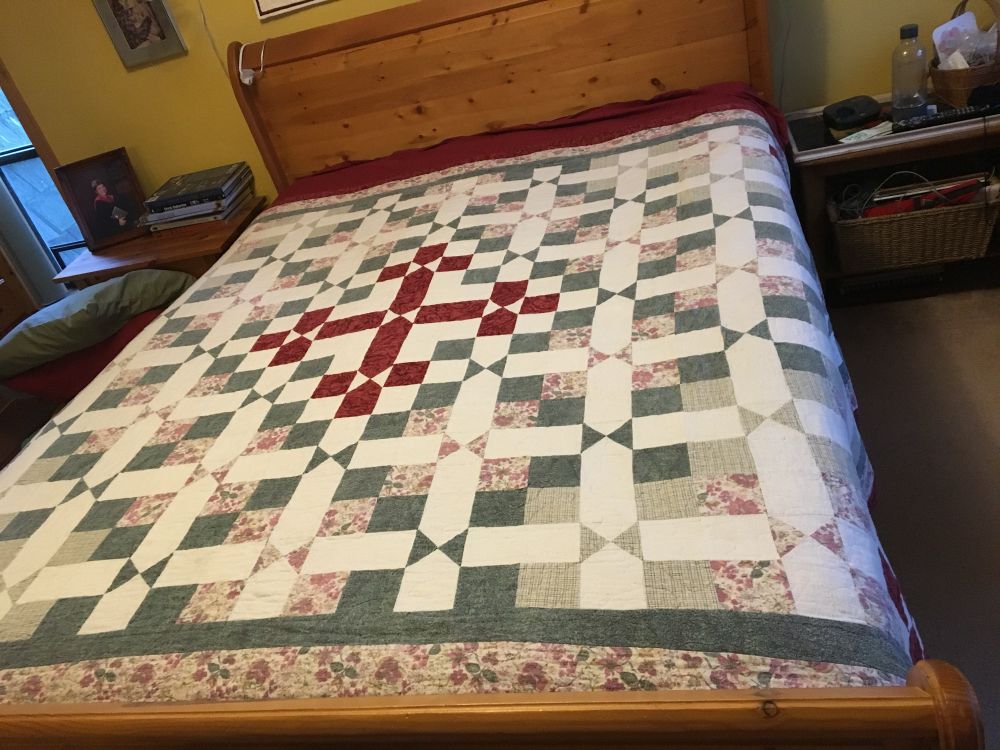 Quilt in cream, green, floral with red on cream centre squares.