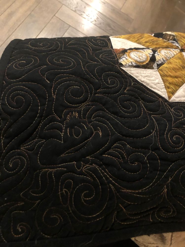‘Whee face’ quilt outline in gold thread on black.

