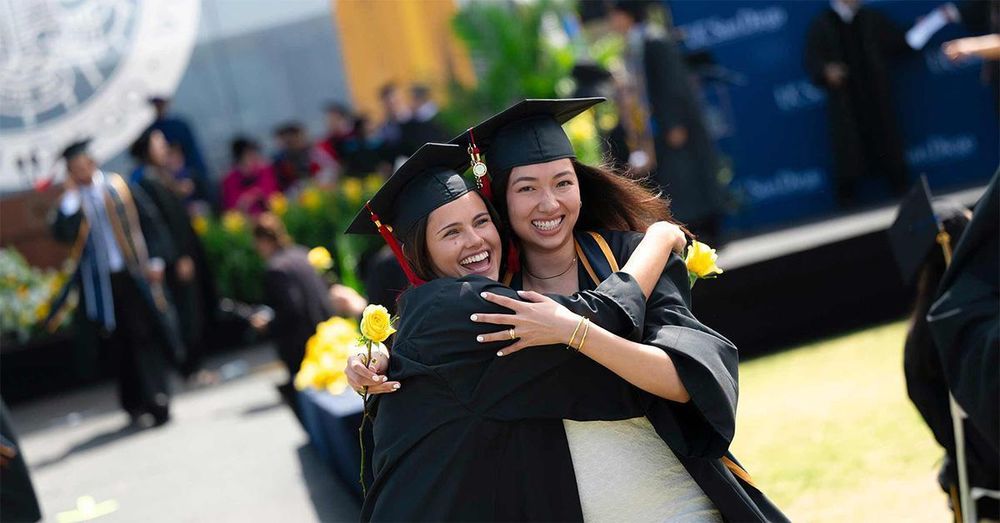 Two graduates smile and embrace