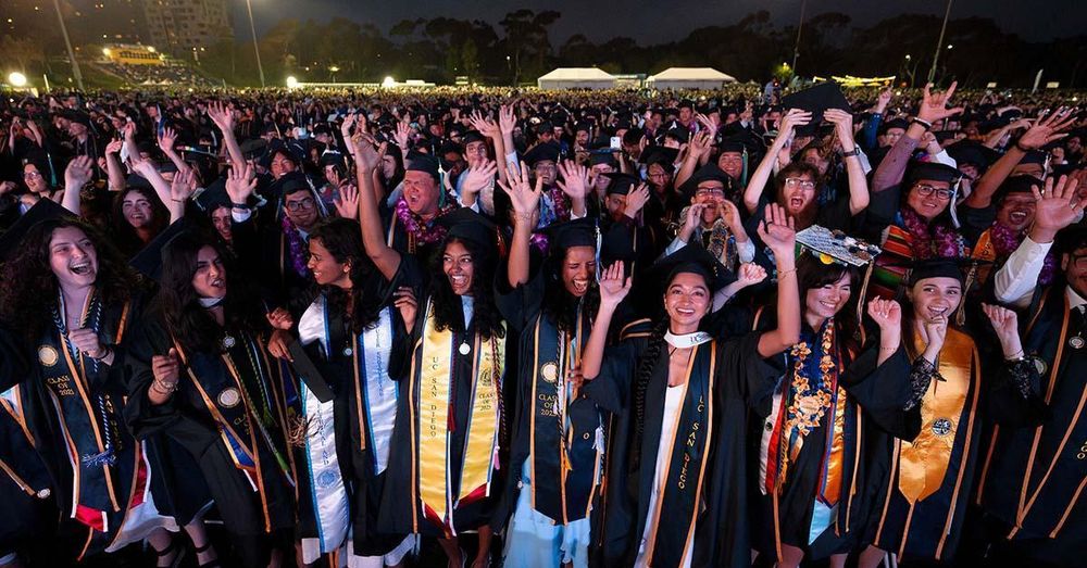 graduates in caps and gowns celebrate with hands in air 