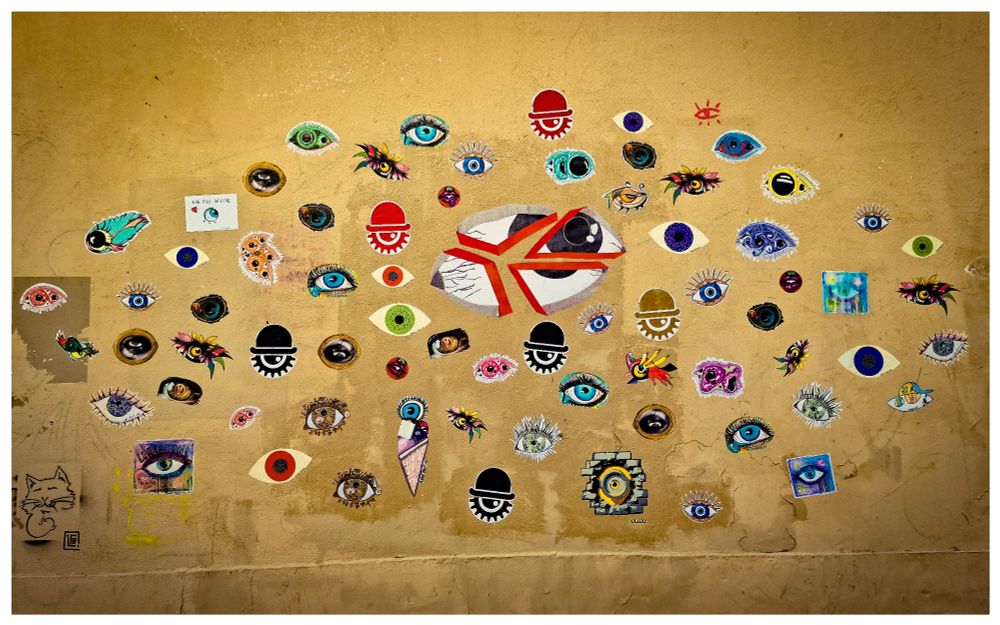 Street arts : dessins représentant des yeux de toute forme et de toutes les couleurs disposés de telle façon qu'ils prennent la forme du contour d'un œil 