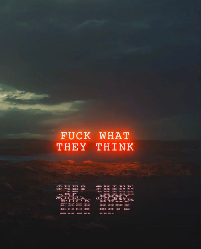 Fuck What They Think, in neon orange text, hovering eerily over a boggy ground, reflected in a small pool of slightly disturbed water, just before sunrise, light fog in the distance, grayish/green clouds in the sky. 