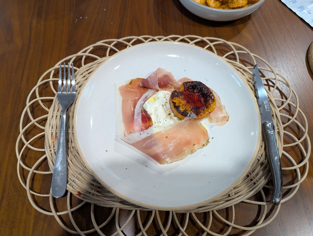 A plate with a charred peach half, burrata, and speck (a thin sliced cured ham). That's really all that's in the dish. The plating is not particularly inspiring.