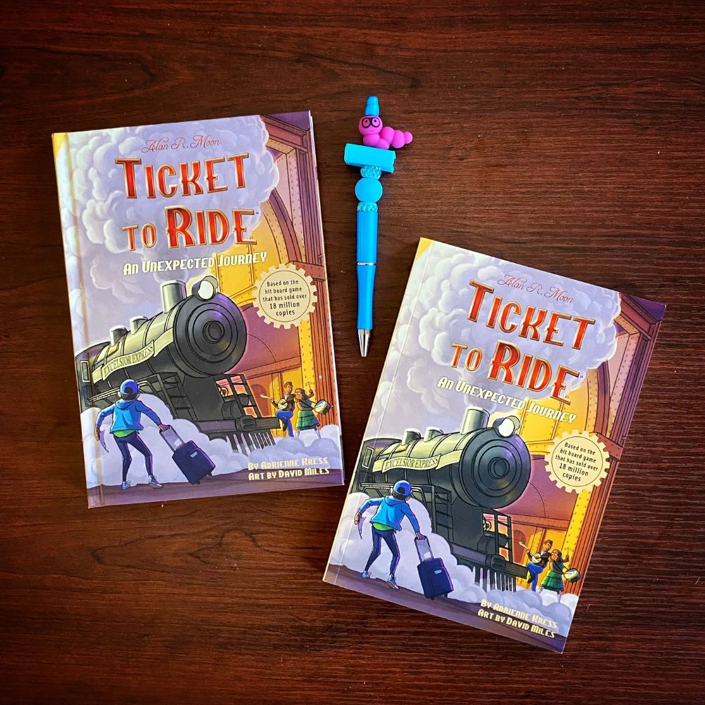 Two versions of TICKET TO RIDE: AN UNEXPECTED JOURNEY - one in hardcover and one in paperback! And a pen with a bookworm charm sitting on top! 