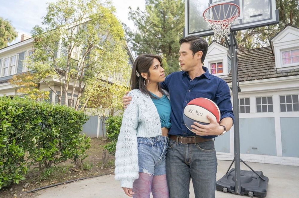 Ben Song (the main character of the 2022 version of Quantum Leap) holds a basketball with one arm, while his other arm is around the shoulder of Gia Mendez. Ben has "leaped" into Gia's father's body, and is having to learn on the fly what it's like to be the father of a young trans girl. Anyway, it's great.