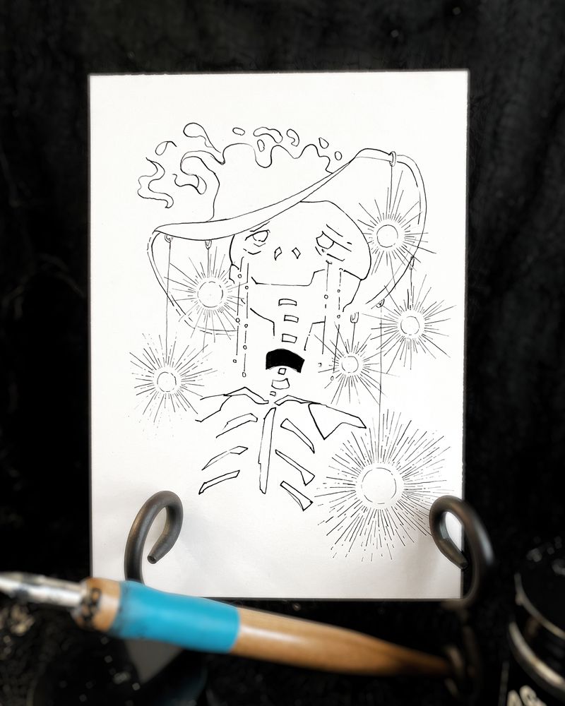 Photograph of a traditional ink illustration. It should a skeleton figure with a large hat disintegrating/becing created at the top. From the hat's brim hands glowing orbs. It looks as though the skull has a melancholy smile. 