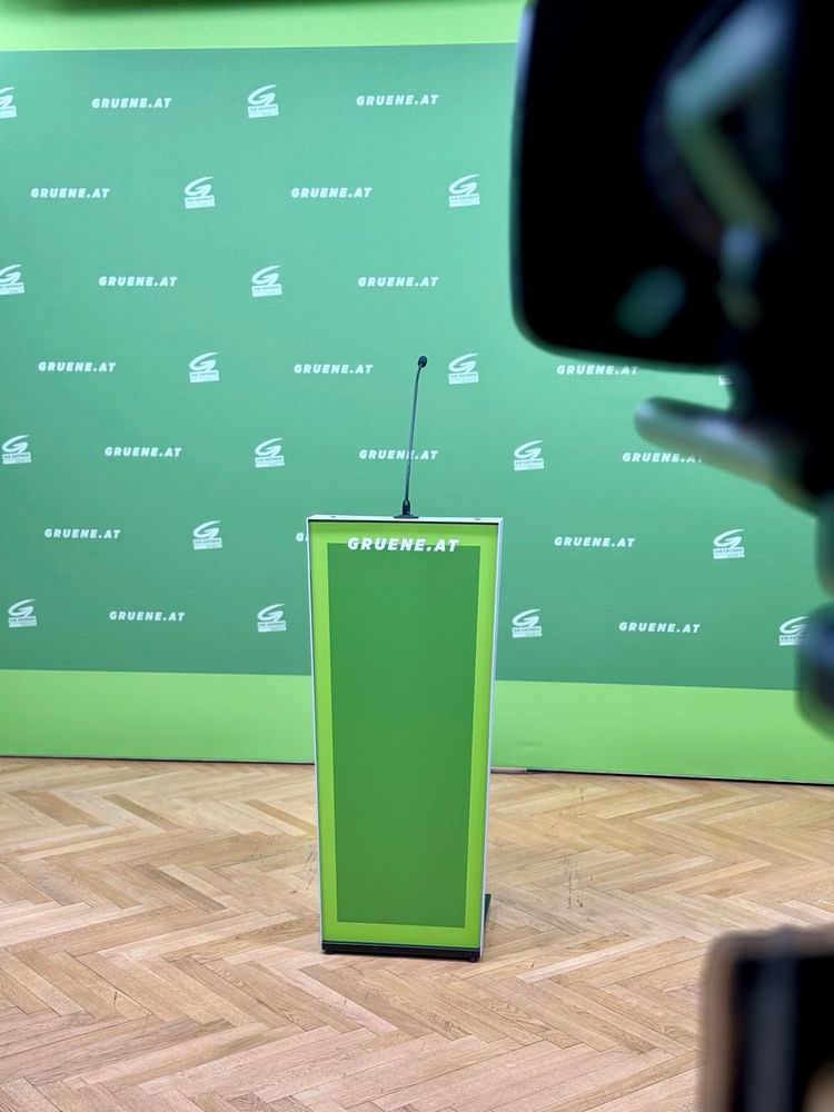 PK-Raum der Grünen: Grünes Rednerinnenpult vor grünem Backdrop, auf dem gruene.at steht