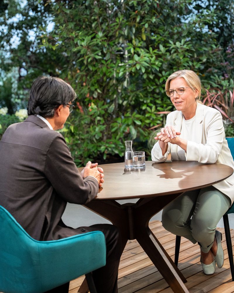 Bild von Leonore Gewessler bei ORF-Sommergespärch, sitzend an einem Tisch.