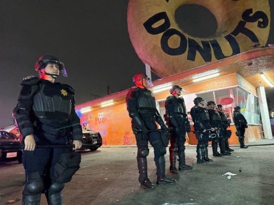 riot cops in a line blocking the drove thru of the iconic Randy's donuts in LA