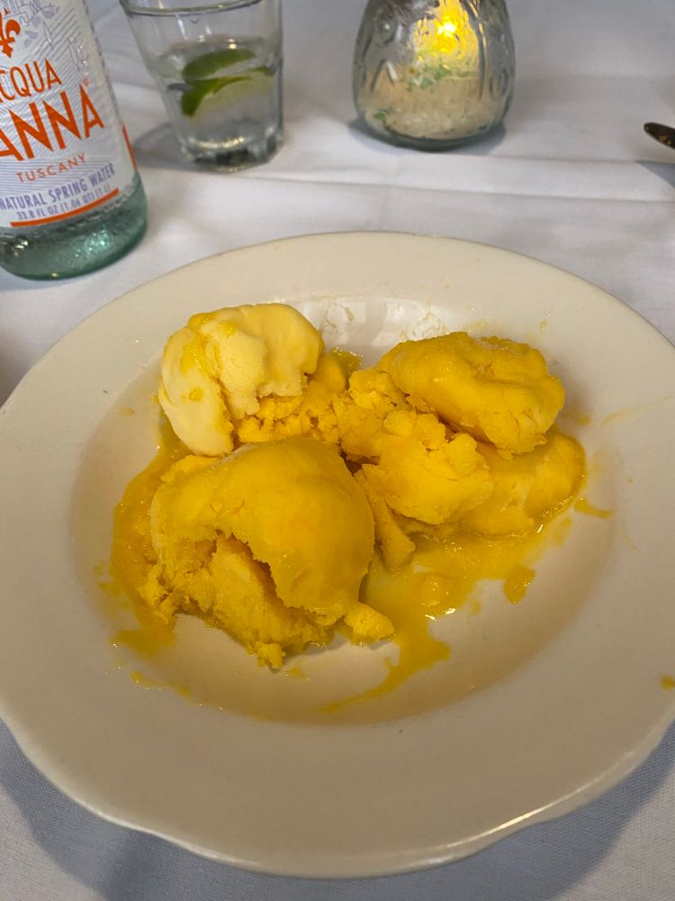 Orange colored Mango Sorbet in a white bowl with Coconut Cream. (Almost ate the whole thing before snapping a picture to share). 