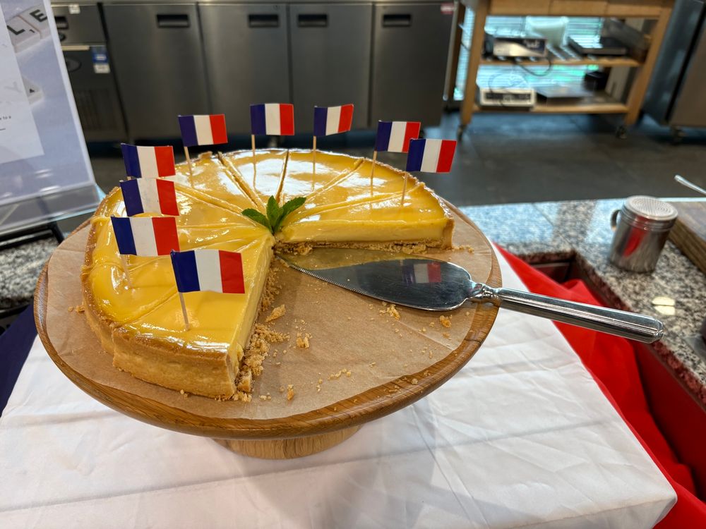 The picture shows a lemon tart with French flags placed around it.