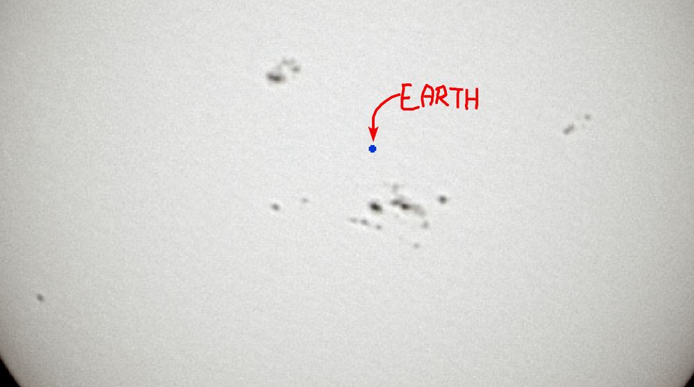 zoomed in view of the previous image, cropped to an area that covers most of the spots. A tiny circle shows the Earth to scale, with a label and an arrow pointing to it that says "EARTH". This tiny circle, containing everyone you know and everywhere you've been, is smaller than almost every single sunspot visible.