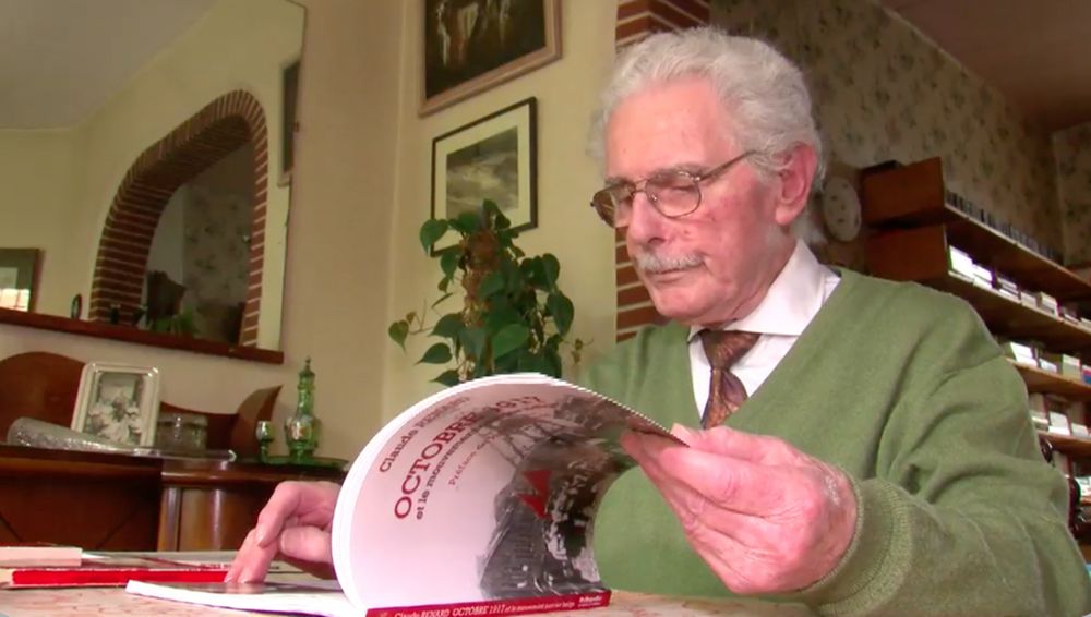 Claude Renard chez lui entrain de consulter son livre.