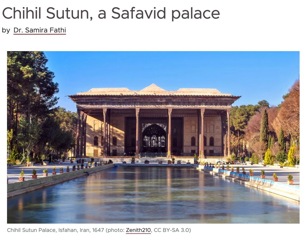 Straight on photo of the palace looking across the reflecting pool against a bright blue sky. Reflections of the columns and the small potted bushes  that line the pool can be seen in the water. Trees frame the palace in the background.