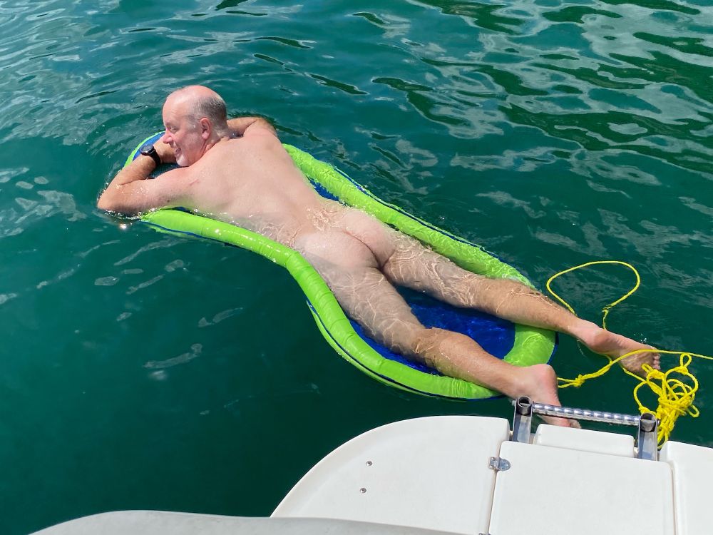 Naked lying down on a float on the lake.