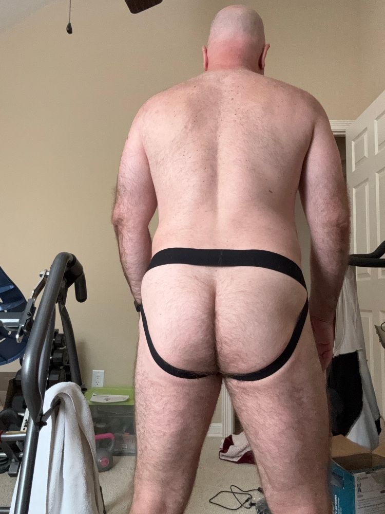 Standing while wearing a jockstrap from behind. 