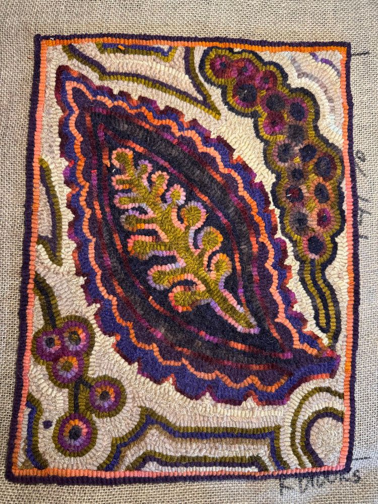 Traditional hooked rug in purples and oranges, leaf design